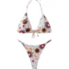 Front flat-lay of a white triangle bikini set with celestial sun, star, and planet print, featuring a gold sun-shaped metal front connector.