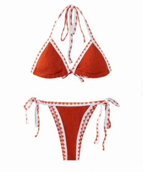 Front flat-lay of a textured orange bikini set with white trim featuring orange zigzag stitching, halter top, and side-tie bottoms.