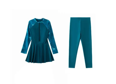 Front flat-lay of the teal swimsuit top, featuring a quarter-zip front closure, tropical-print raglan sleeves, and a peplum waist.
