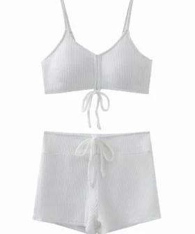 Macro close-up of white ribbed swimsuit fabric, inner lining, and a spaghetti strap connected via a metal ring.