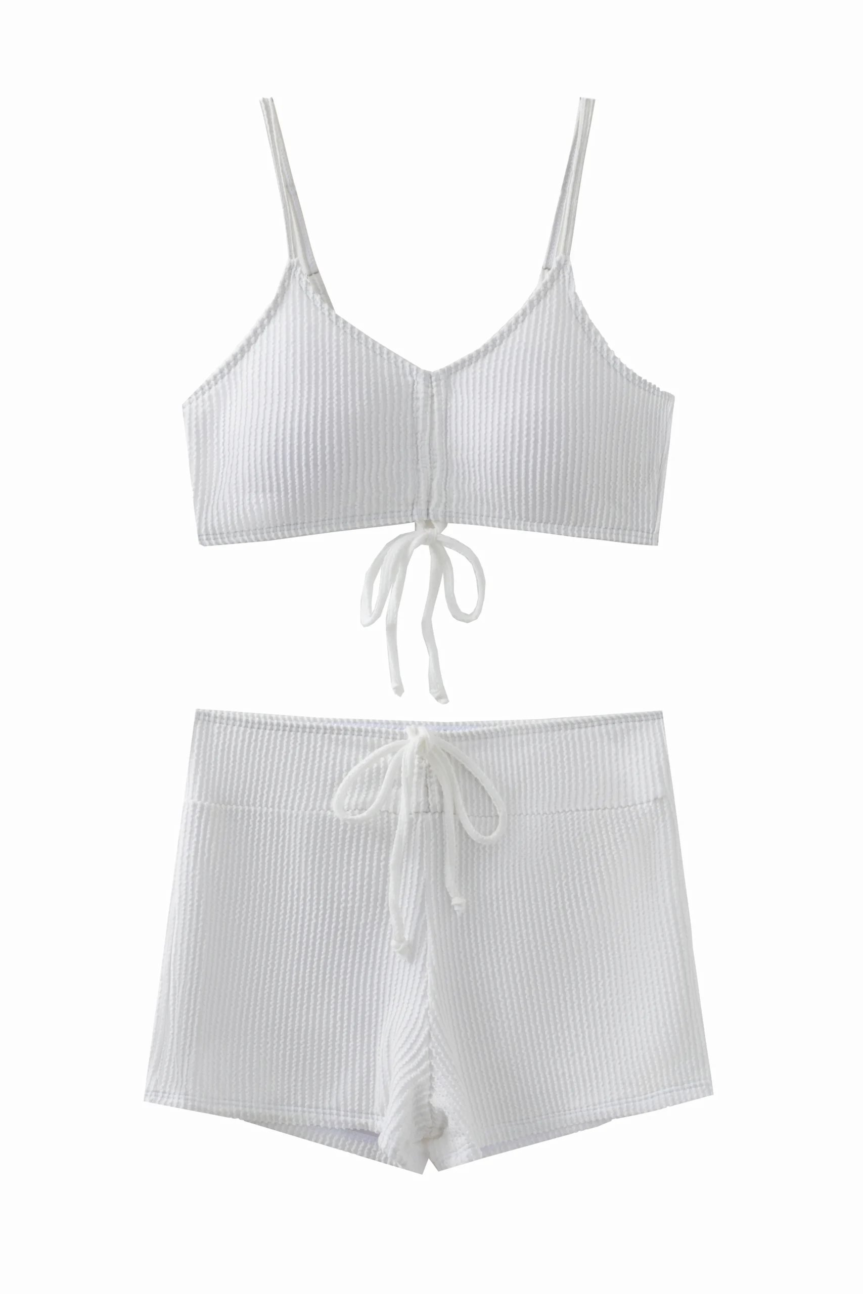 Macro close-up of white ribbed swimsuit fabric, inner lining, and a spaghetti strap connected via a metal ring.