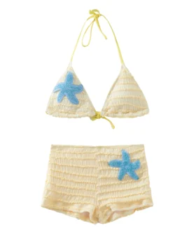 Close-up view of a blue sequined starfish patch appliqué on highly textured pale yellow smocked fabric.