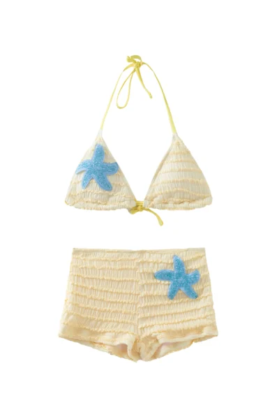 Close-up view of a blue sequined starfish patch appliqué on highly textured pale yellow smocked fabric.