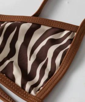 Macro close-up of the zebra print bikini top's neckline showing the brown contrast binding and stitched strap.