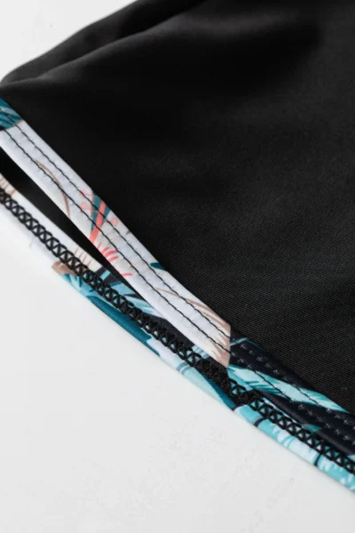 Macro close-up of folded solid black swimwear fabric, highlighting its smooth, stretchy texture.