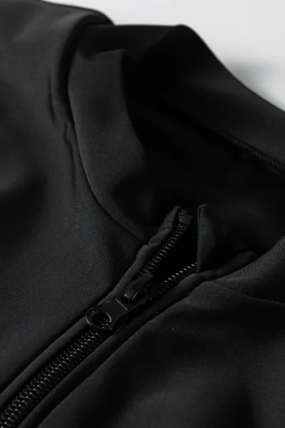 Macro close-up of the elastic waistband on the solid black swim leggings, showing gathered fabric, double stitching, and a white tag.