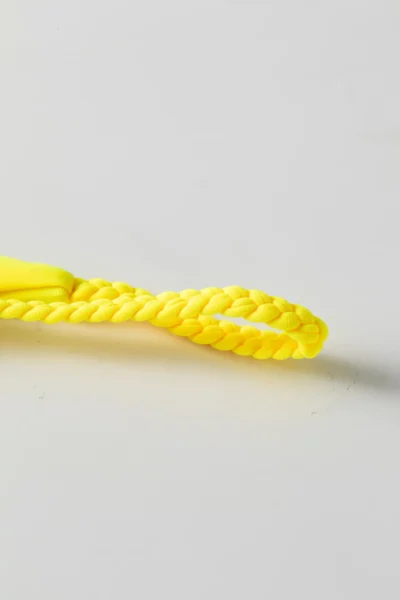 Macro close-up of a yellow braided twist tie strap for a bikini, isolated on a white background.