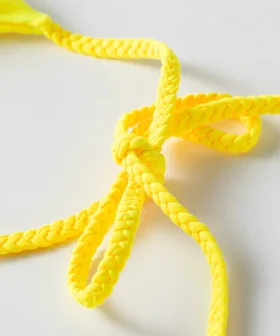 Macro close-up of a yellow braided twist tie strap tied into a knot/bow.