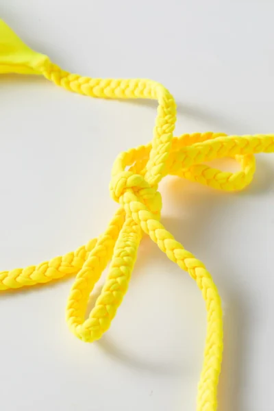 Macro close-up of a yellow braided twist tie strap tied into a knot/bow.