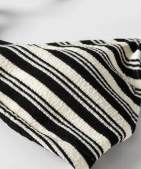 Close-up of black and white striped terry fabric showing the white inner lining peeking out from the edge.