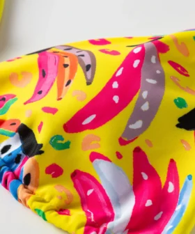 Macro close-up of colorful abstract print featuring pink, grey, and blue shapes on a yellow fabric base.