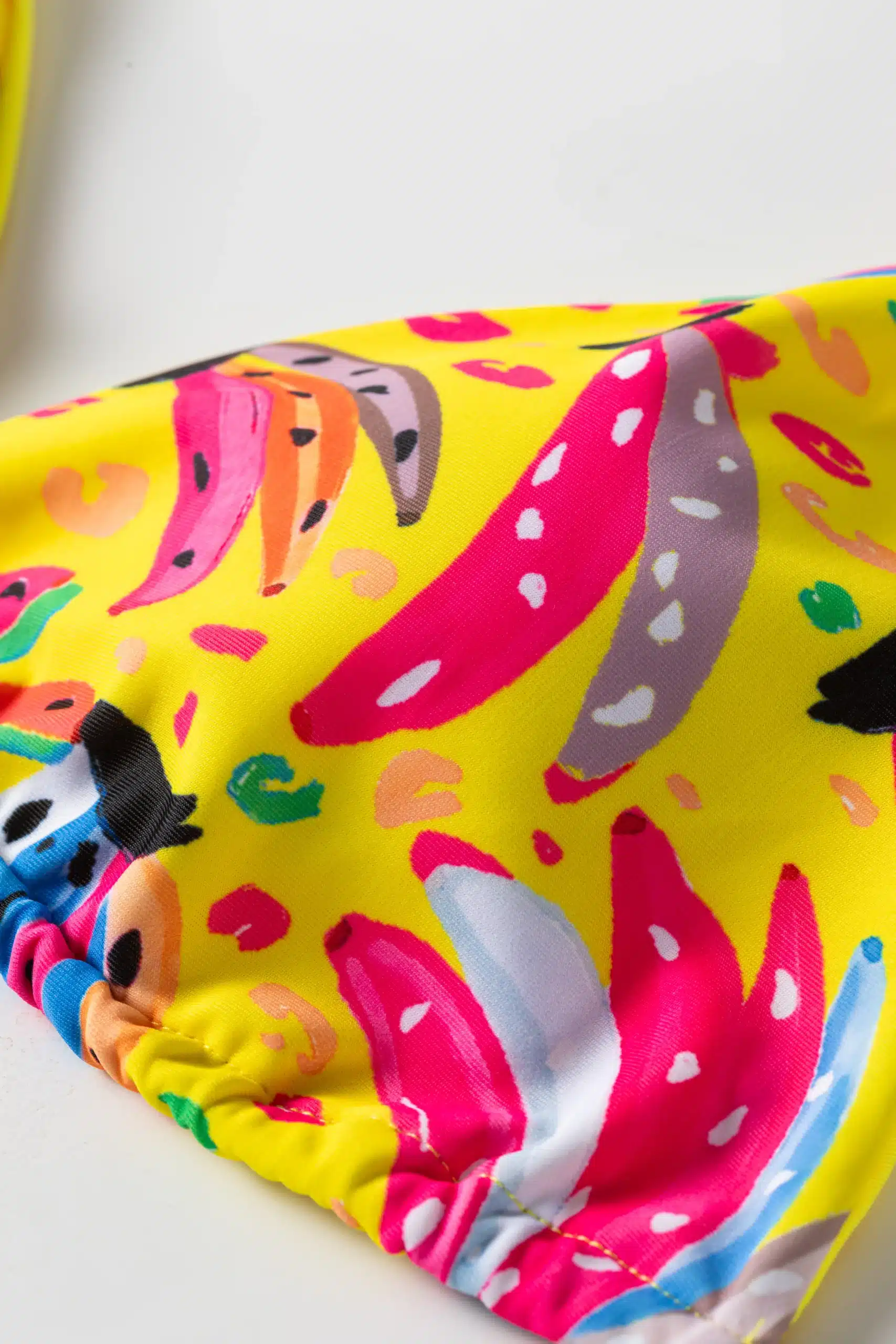 Macro close-up of colorful abstract print featuring pink, grey, and blue shapes on a yellow fabric base.