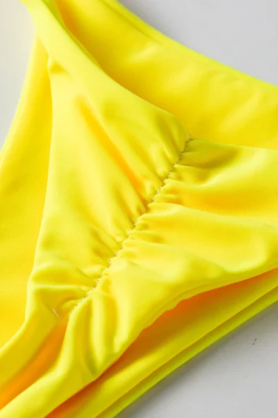 Macro close-up of the ruched stitching detail inside the yellow bikini bottom.