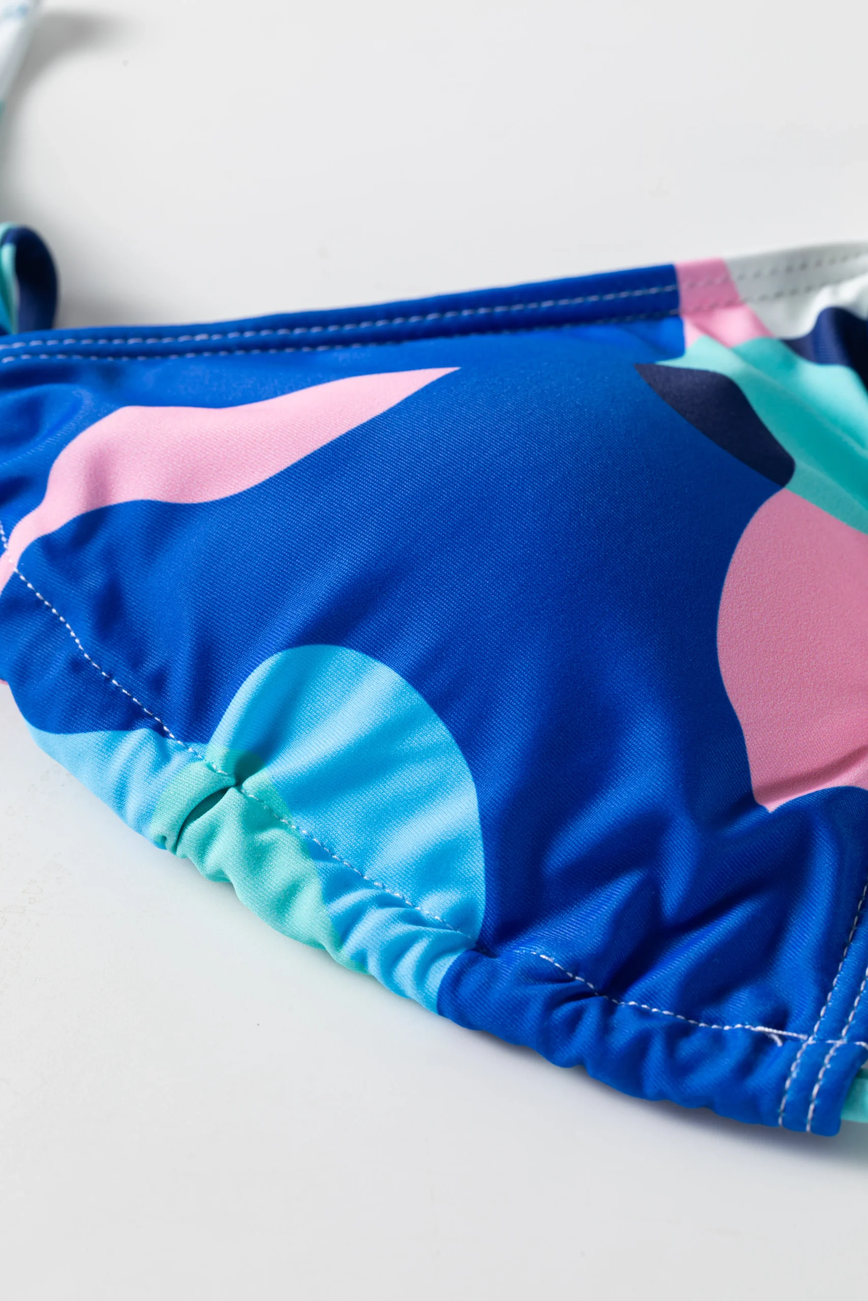 Back flat-lay of the abstract print long-sleeve cover-up and triangle bikini set, revealing the bikini top's white inner lining.