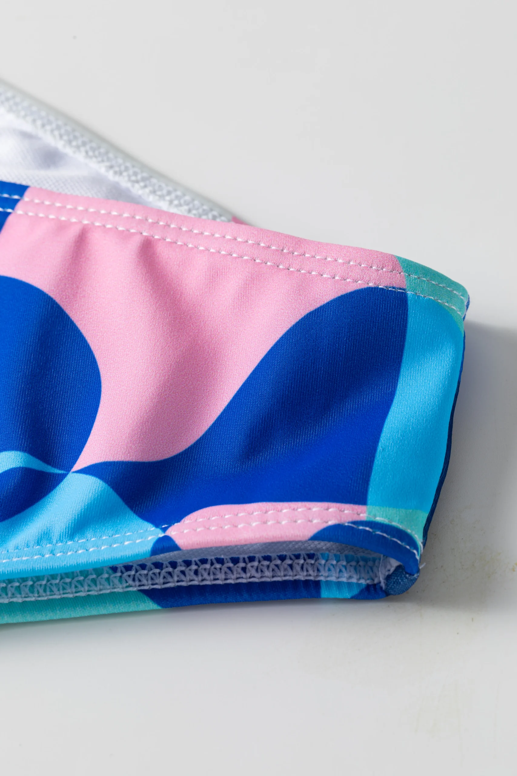 Front flat-lay of the abstract print triangle bikini set with thin neck ties and matching bottoms.