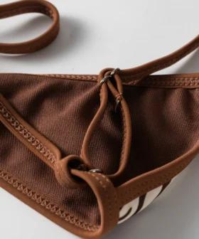 Macro close-up of the back fabric of the bikini top showing the brown mesh lining, binding, and metal ring for the strap.