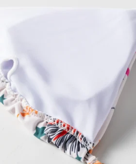 Macro close-up of the inside lining of a white bikini top, showing the white liner, overlock stitching, and a fabric loop.