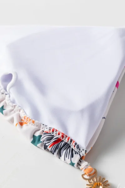 Macro close-up of the inside lining of a white bikini top, showing the white liner, overlock stitching, and a fabric loop.