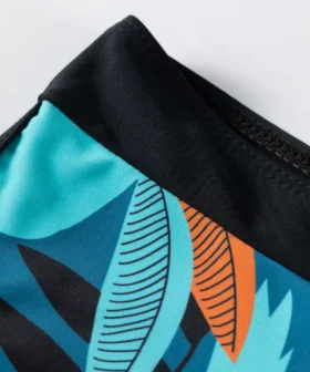 Macro close-up of the black drawstring ties tied into a knot on the front of the bikini top, resting against the orange and teal printed hem.
