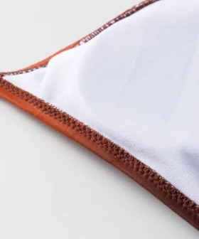Macro close-up of the bikini garment's white inner lining, revealing the neat zigzag stitching along the edge.