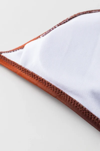 Macro close-up of the bikini garment's white inner lining, revealing the neat zigzag stitching along the edge.