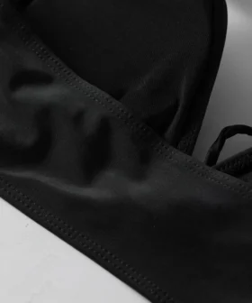 Macro close-up of a wide black fabric halter strap tied into a knotted loop.