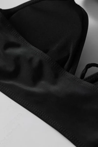 Macro close-up of a wide black fabric halter strap tied into a knotted loop.