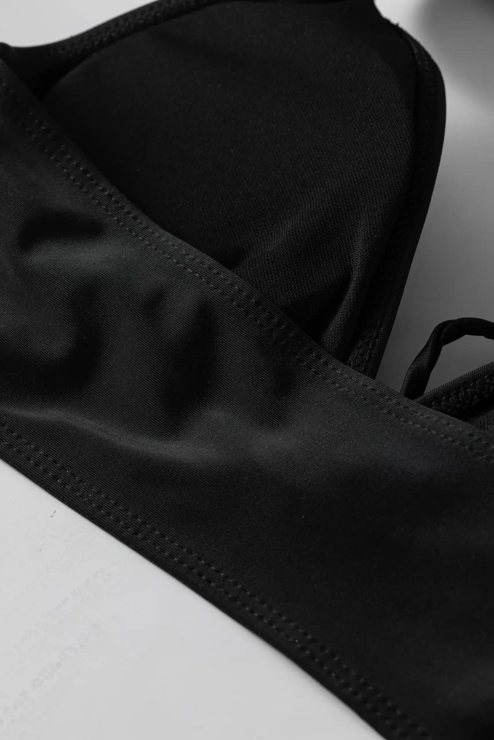 Macro close-up of a wide black fabric halter strap tied into a knotted loop.