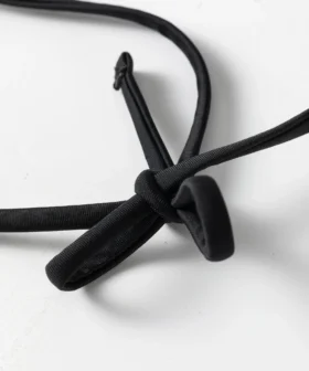 Close-up showing a thin black spaghetti strap attached to the black and white striped bikini fabric.