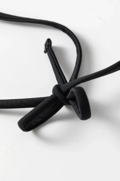 Close-up showing a thin black spaghetti strap attached to the black and white striped bikini fabric.