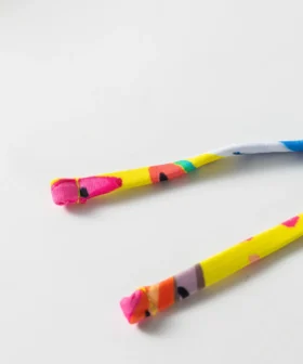 Macro close-up of the folded and stitched ends of colorful patterned bikini tie strings.