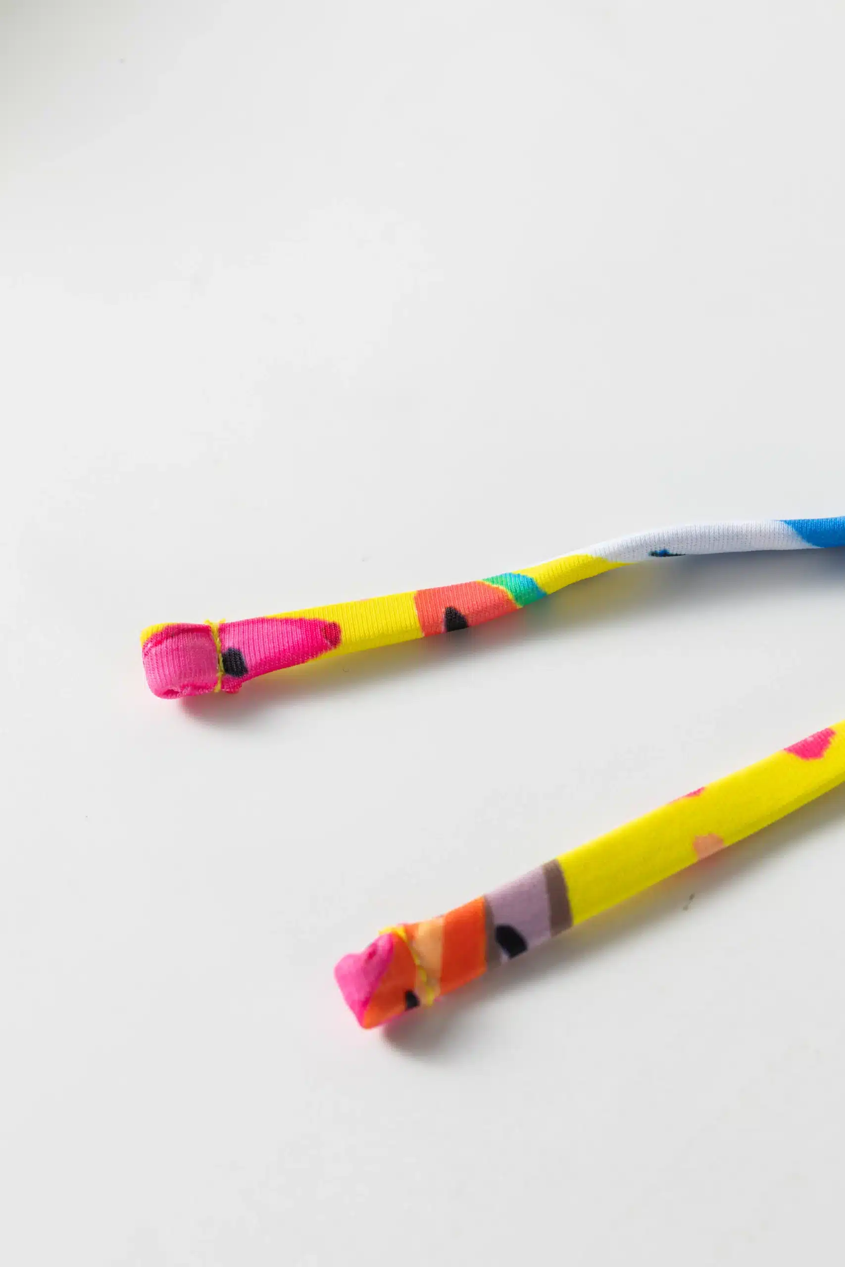 Macro close-up of the folded and stitched ends of colorful patterned bikini tie strings.