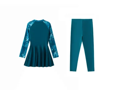 Front flat-lay of a teal long-sleeve swimsuit with a peplum waist and tropical print sleeves, paired with matching solid teal leggings.