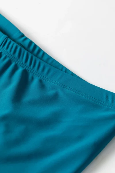 Front flat-lay of a complete teal modest swimsuit set, featuring a top with a peplum waist and tropical sleeves, paired with solid swim leggings.
