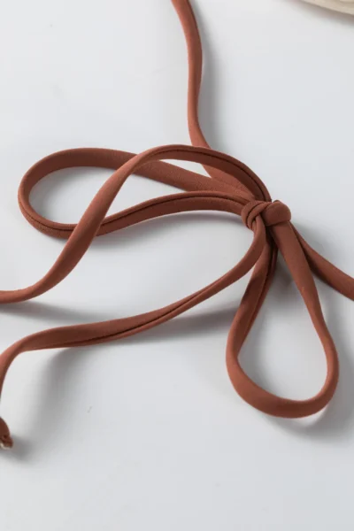 Back flat-lay of the ivory textured bikini set showing the white inner lining, gold front ring, and brown ties.