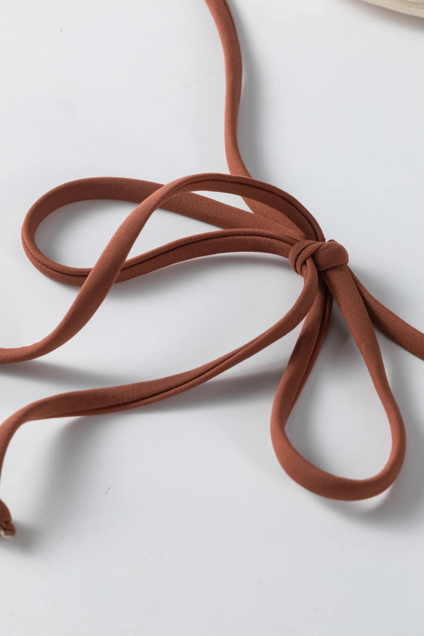 Back flat-lay of the ivory textured bikini set showing the white inner lining, gold front ring, and brown ties.