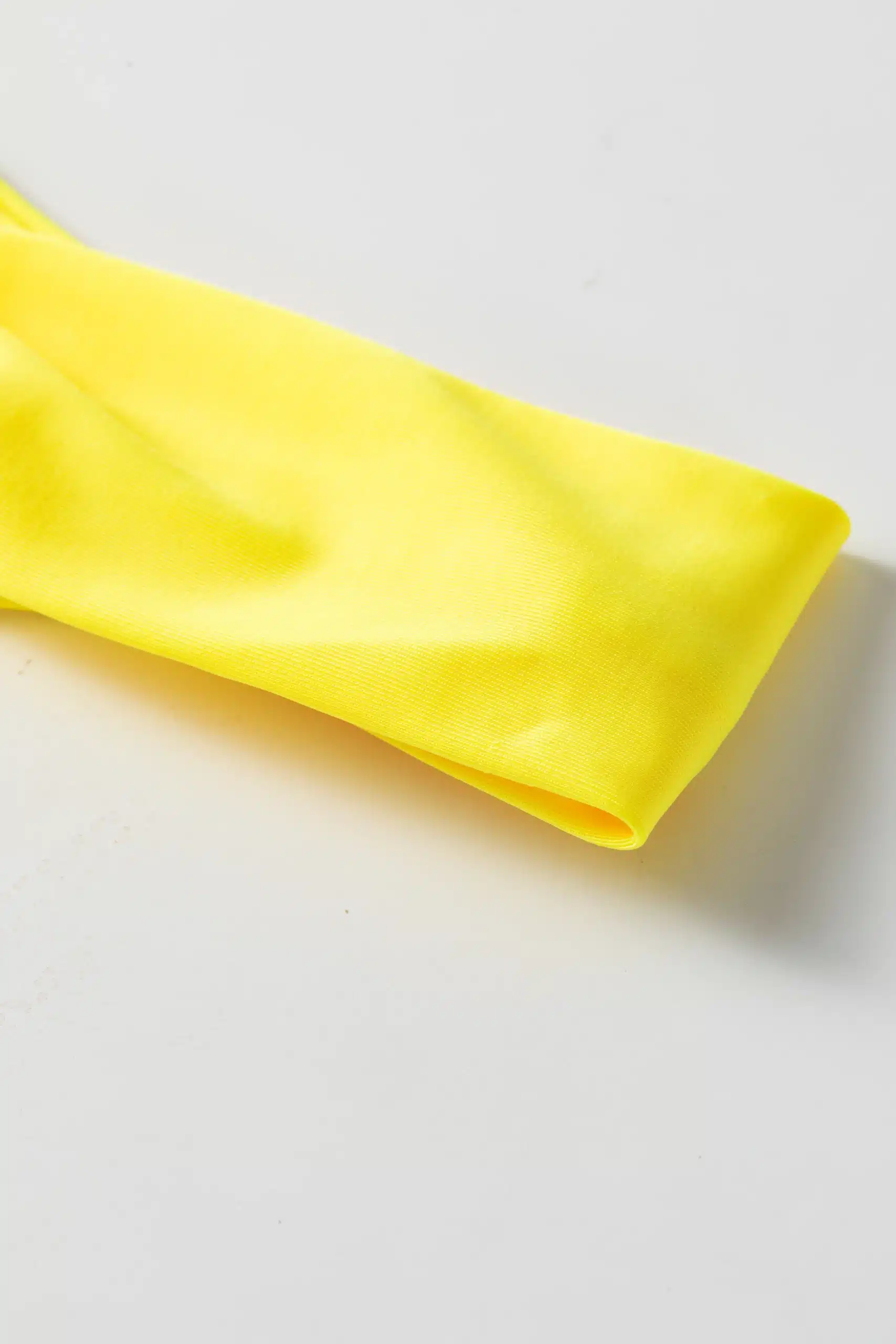 Macro close-up of smooth solid yellow bikini fabric edge and fold.