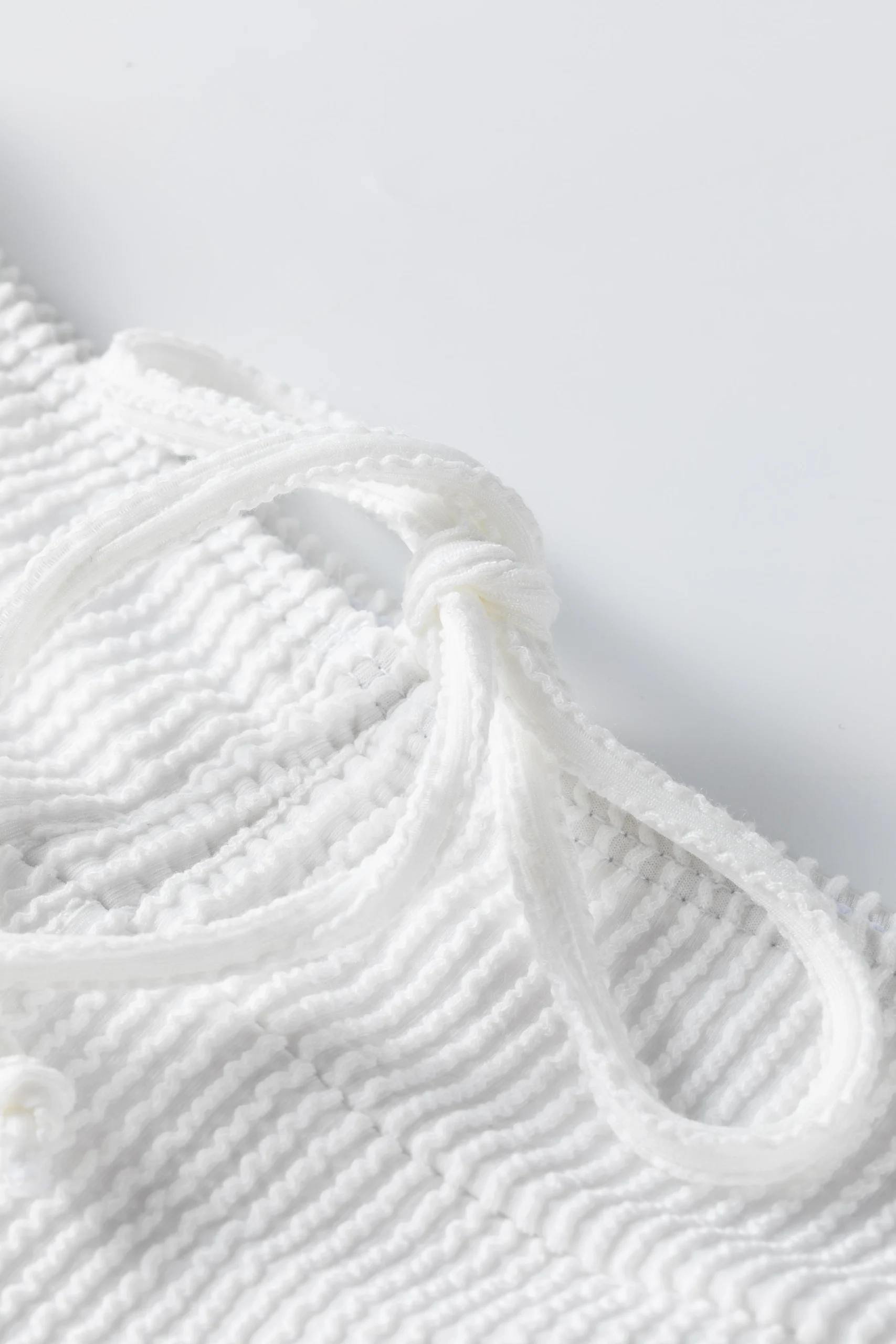 Macro close-up of two flat white elastic bikini straps with zigzag edge stitching