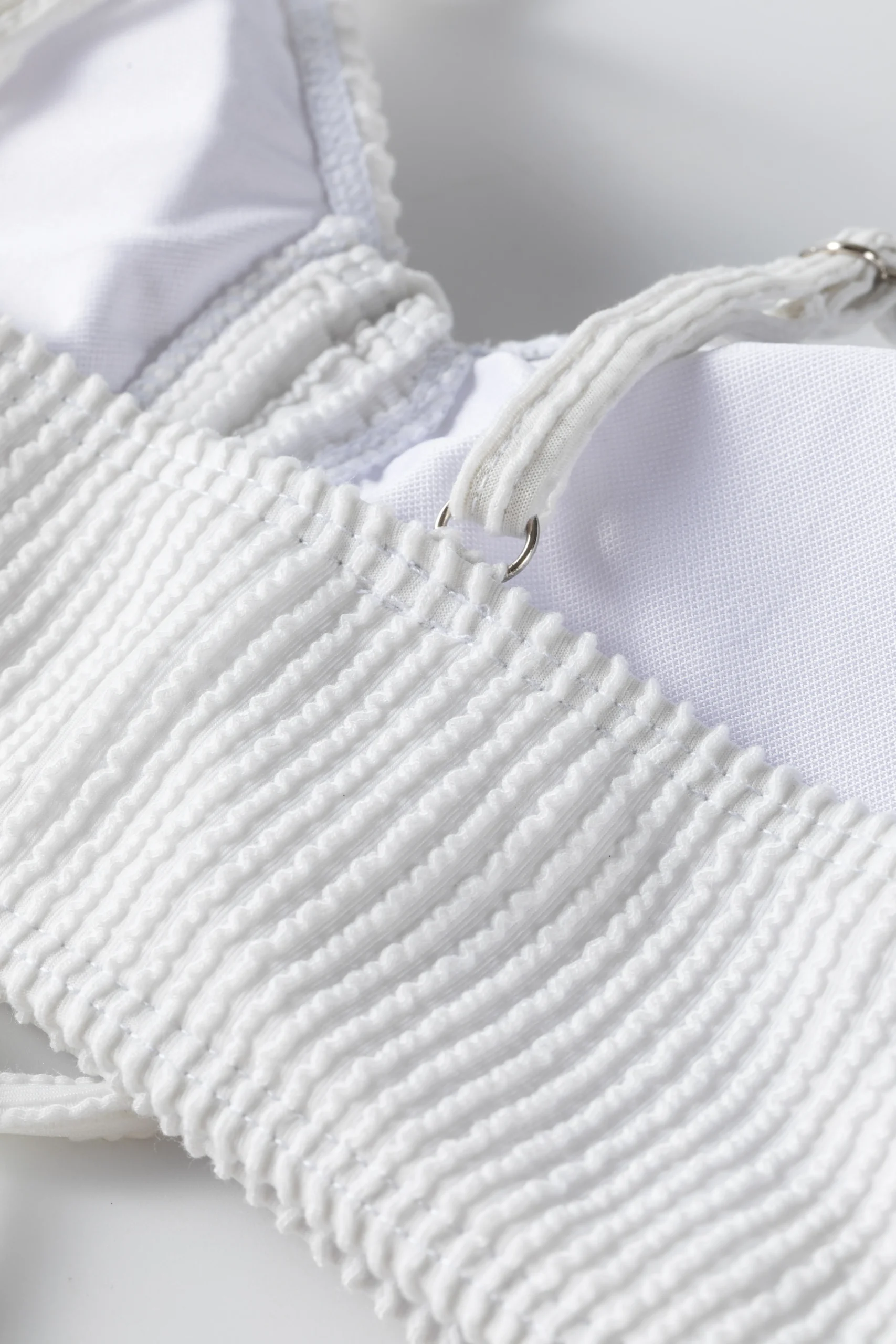 Close-up detail of a thin white tubular bikini string tied tightly into a knot.