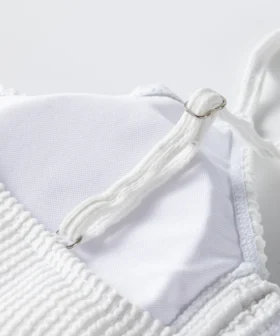 Front flat-lay view of a white two-piece bikini set with ruffled edges and thin tie strings.