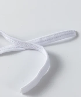 Close-up detail of tightly gathered white ruffle trim on solid white bikini fabric.