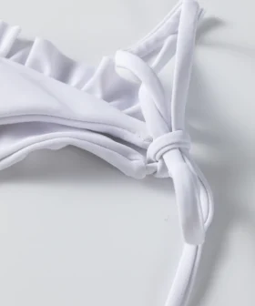Macro close-up of folded solid white bikini fabric, showing the smooth edge and soft texture.