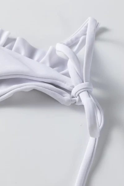 Macro close-up of folded solid white bikini fabric, showing the smooth edge and soft texture.