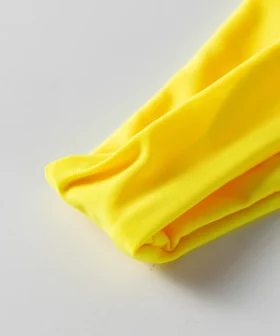Macro close-up showing the soft texture and fold of yellow bikini fabric.