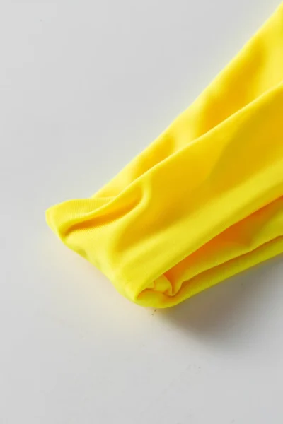 Macro close-up showing the soft texture and fold of yellow bikini fabric.