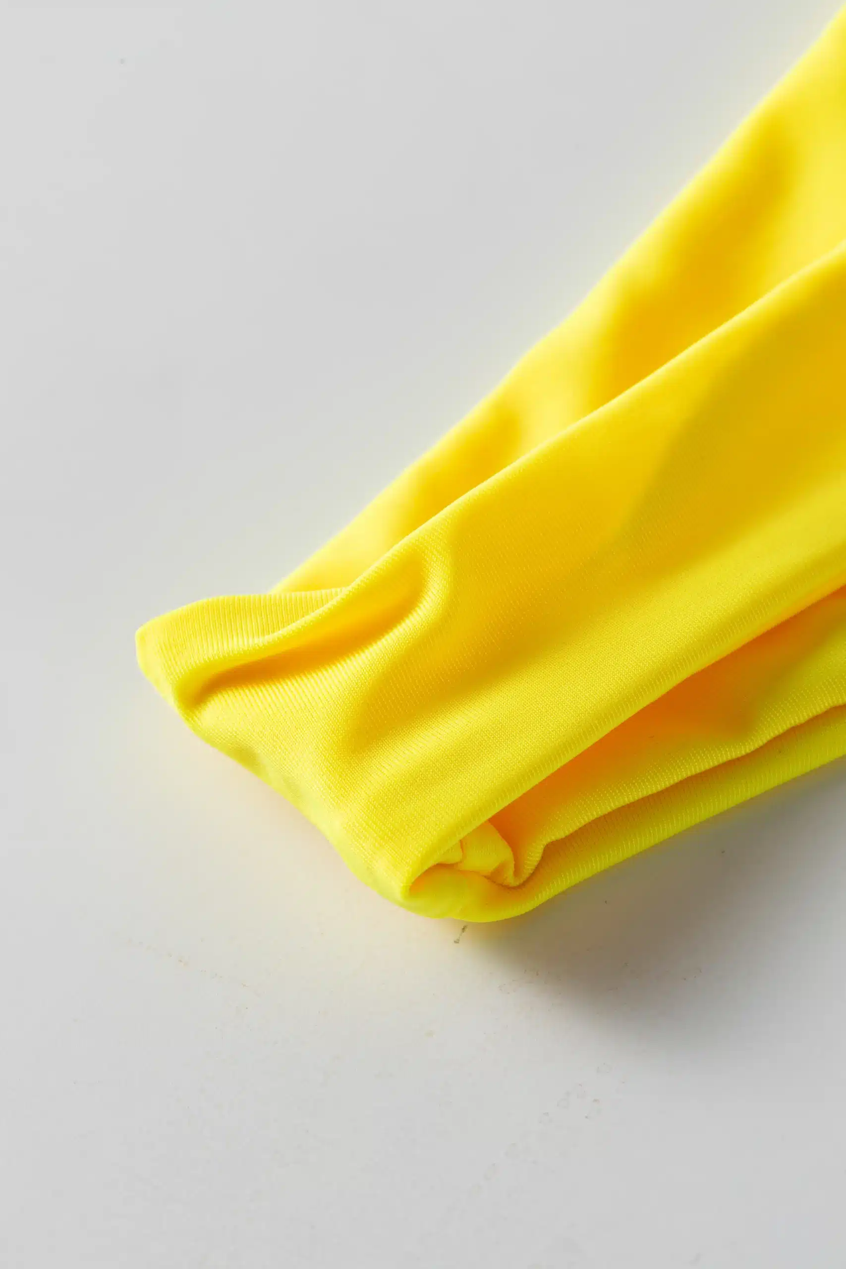 Macro close-up showing the soft texture and fold of yellow bikini fabric.