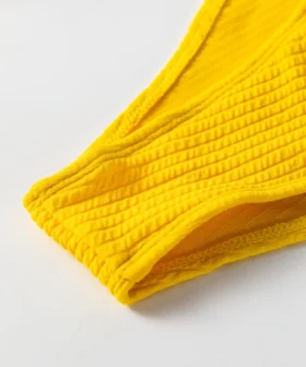 Close-up of yellow ribbed bikini bottom edge showing white inner lining and hem stitching.