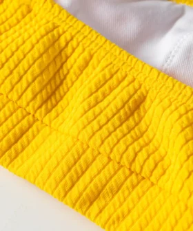 Macro detail of yellow ribbed bikini top showing white inner lining, hem, and silver metal ring. SEO: