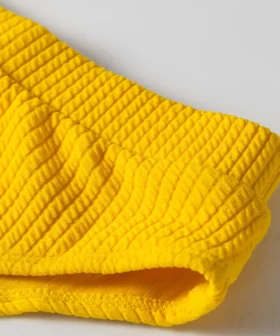 Close-up of yellow ribbed bikini fabric texture and gusset area with white lining.