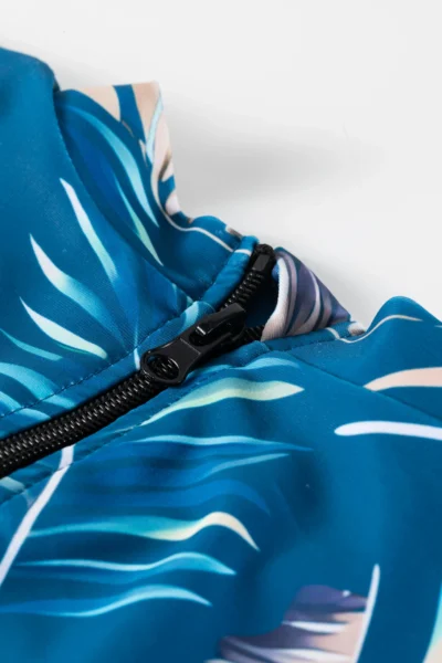 Back flat-lay of the teal tropical print short-sleeve onesie and matching solid teal swim shorts.